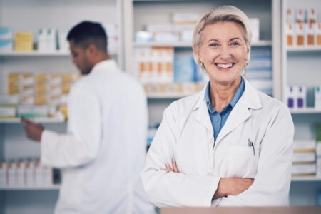 2 personnes dont 1 pharmacienne debout qui est très souriante