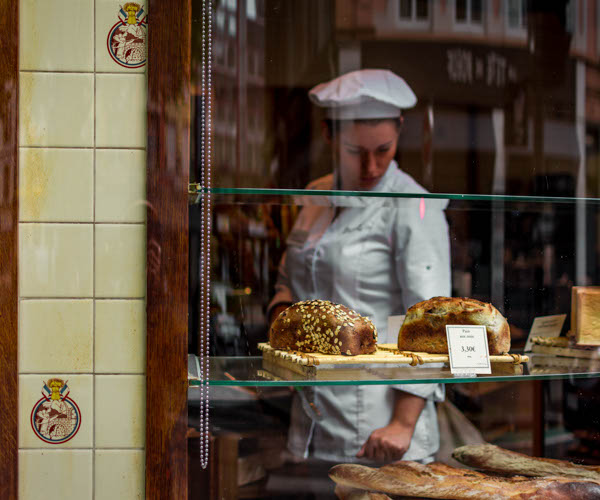 boulangère qui regarde ses pains et brioches dans sa boutique