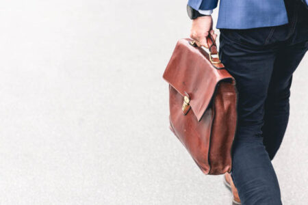 homme avec une veste bleu portant une sacoche marron