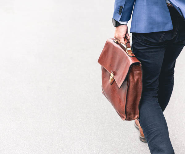 homme avec une veste bleu portant une sacoche marron
