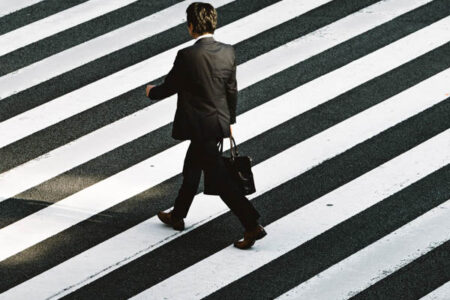 homme en costume noir qui marche avec une sacoche noire