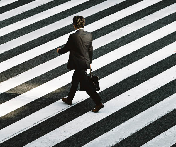homme en costume noir qui marche avec une sacoche noire