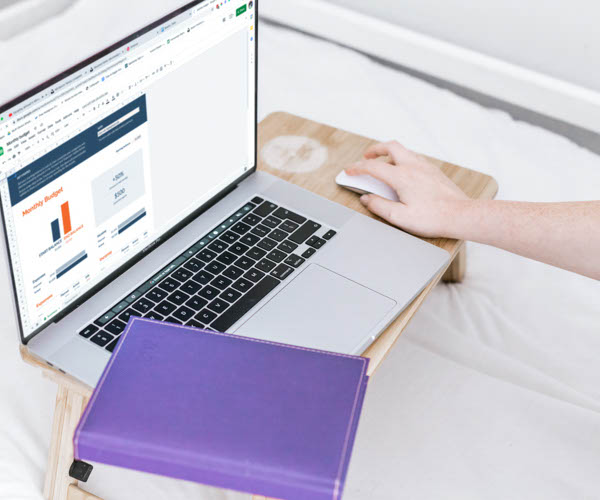 Une main sur une souris d'ordinateur avec un bloc notes violet